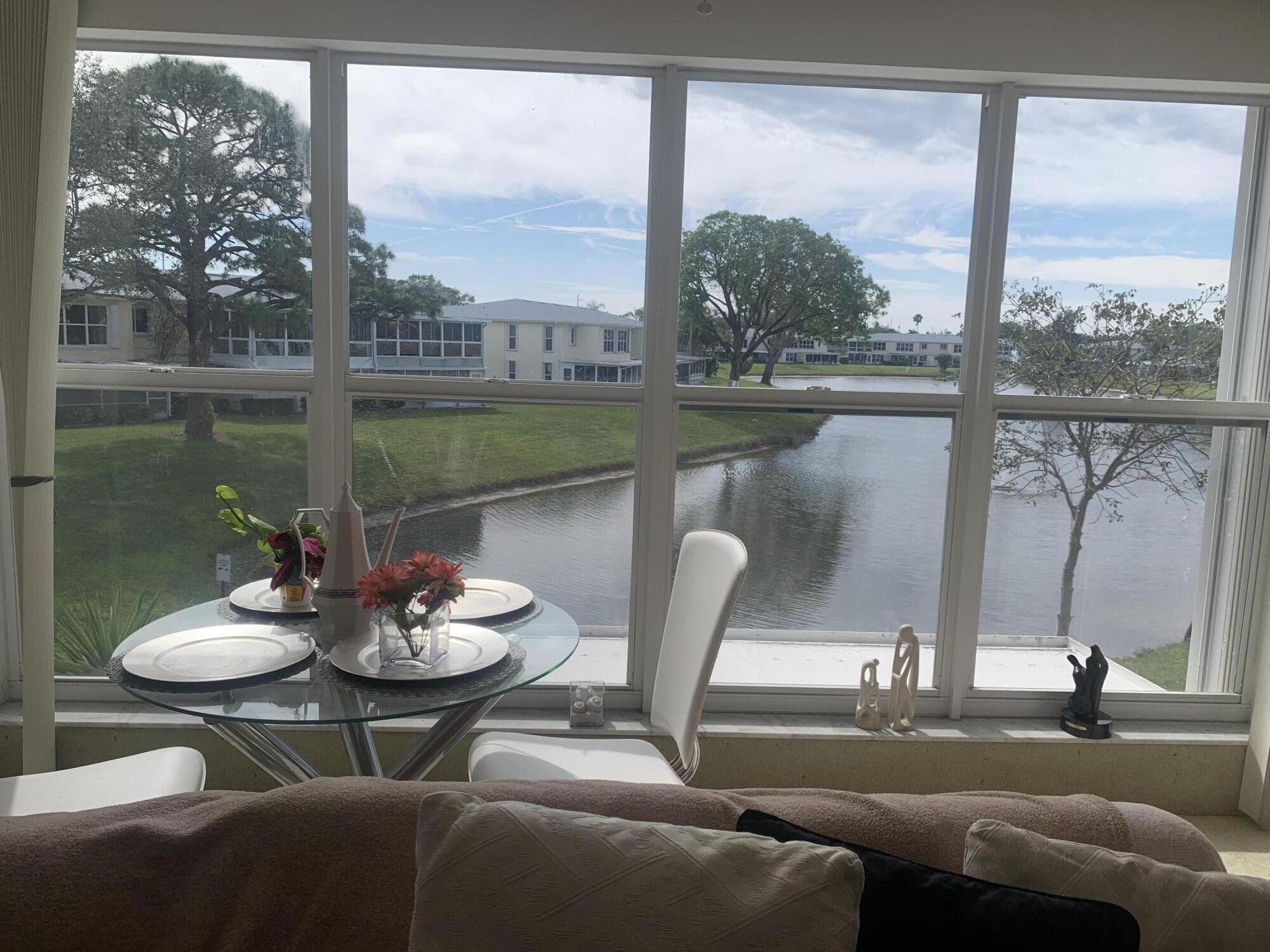 a view of a patio with couches chairs and floor to ceiling window with lake view