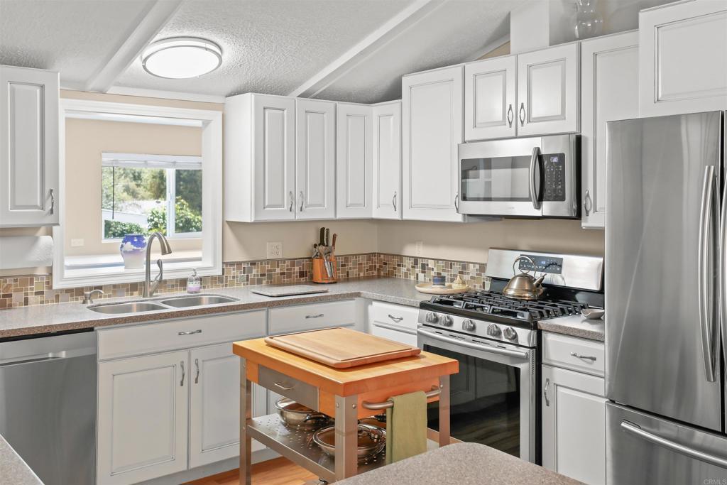 a kitchen with stainless steel appliances granite countertop a stove a sink dishwasher and a refrigerator