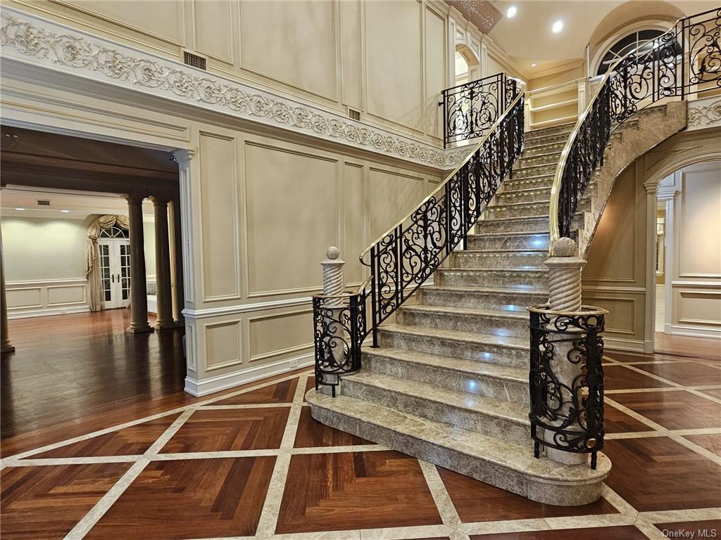 Stairs with a high ceiling, parquet flooring, ornate columns, and ornamental molding