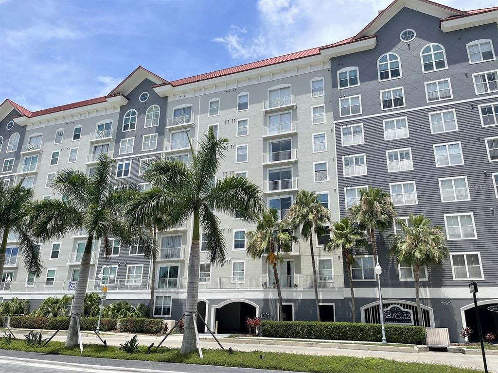 a front view of multi story residential apartment building with yard and parking space