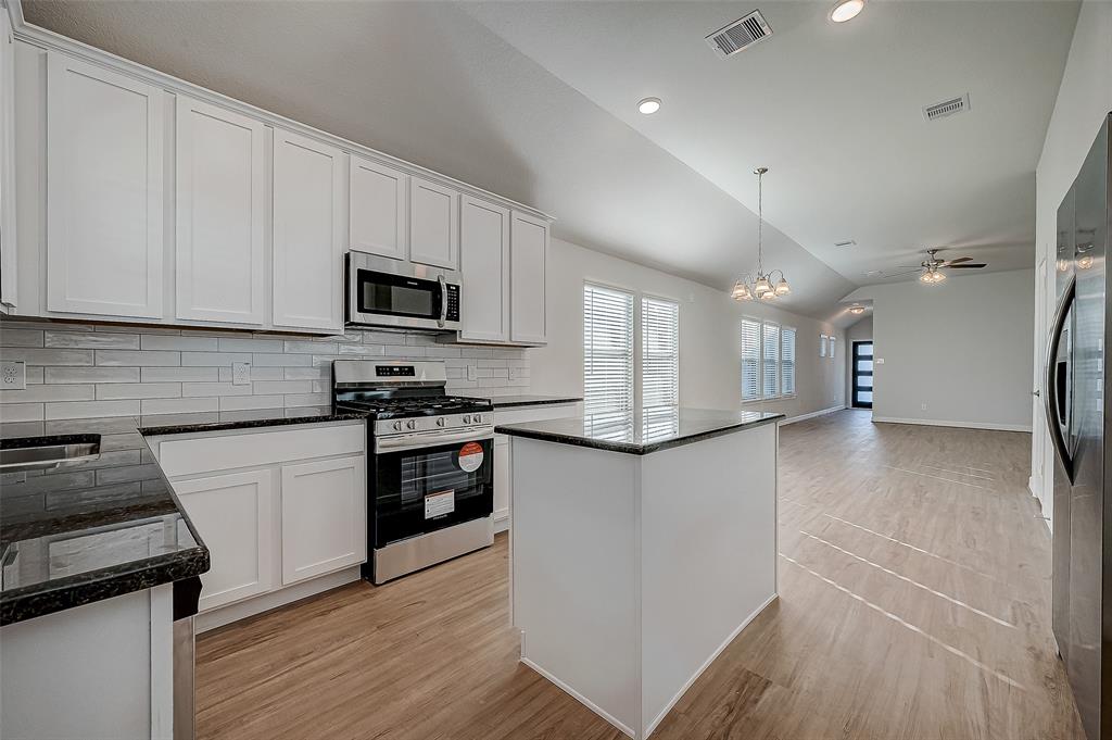 a kitchen with granite countertop a refrigerator stove top oven and sink