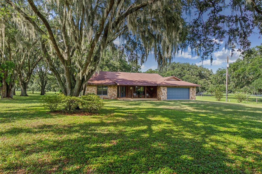 a view of a house with a big yard potted plants and large trees