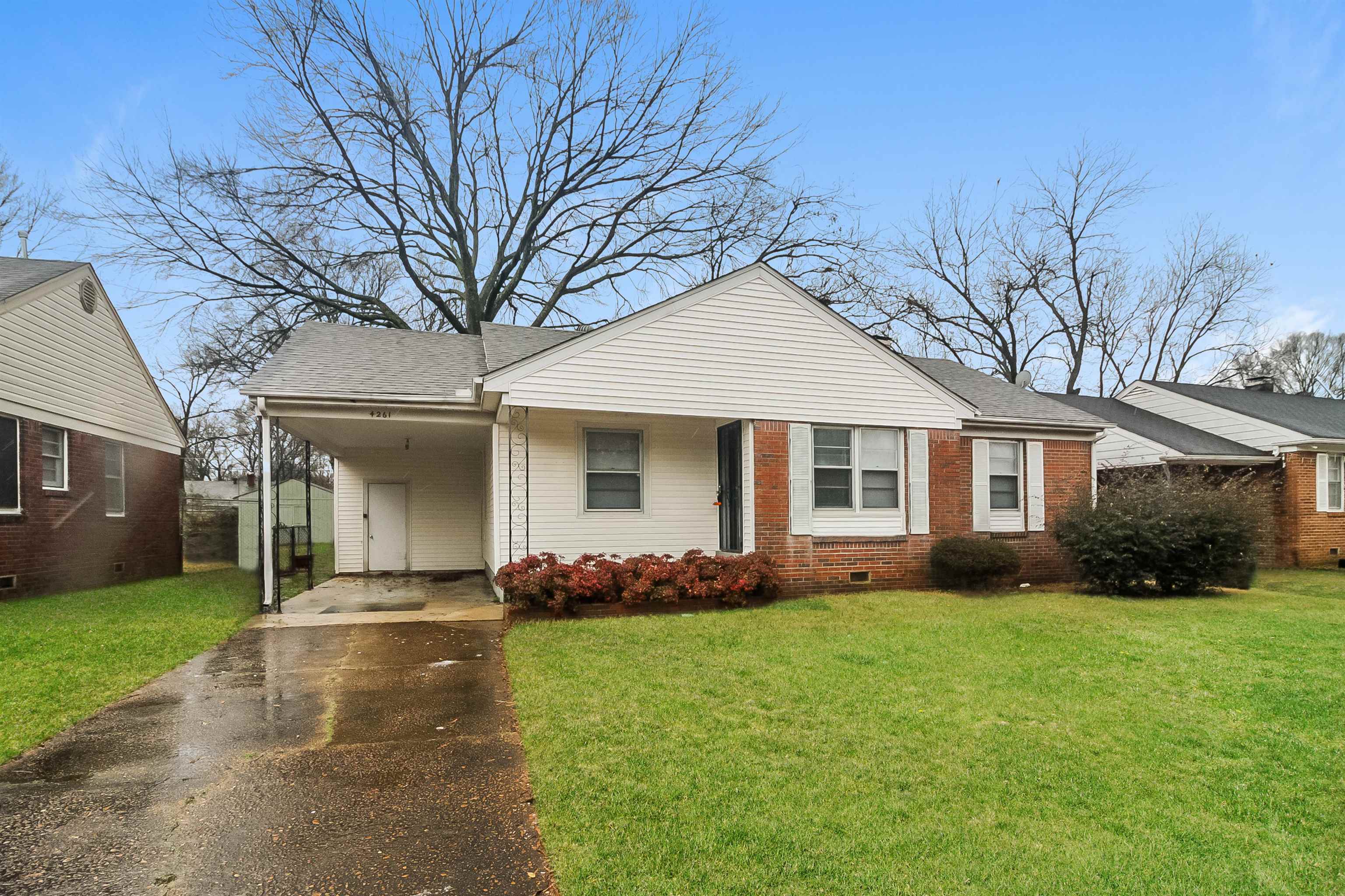 View of front facade featuring a front lawn and a carport