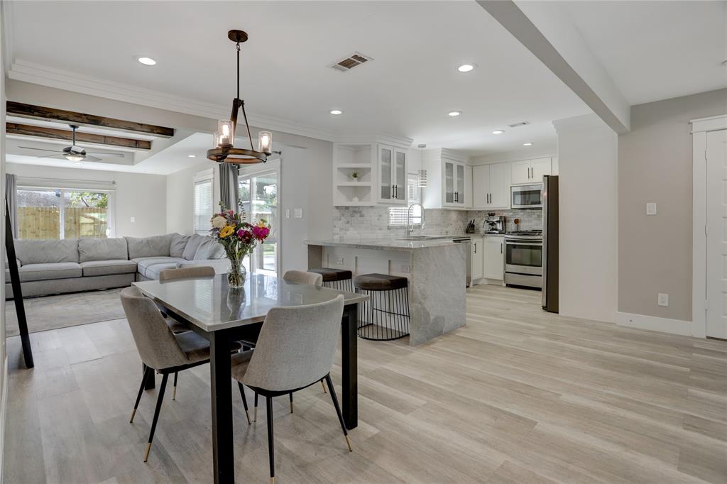 This photo showcases a modern open-plan living area with a combined kitchen, dining, and living space, featuring sleek finishes, stainless steel appliances, and abundant natural light.