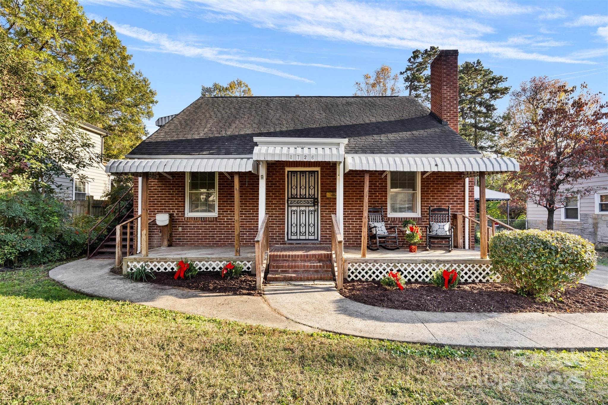 a front view of a house with a yard outdoor seating and covered with trees