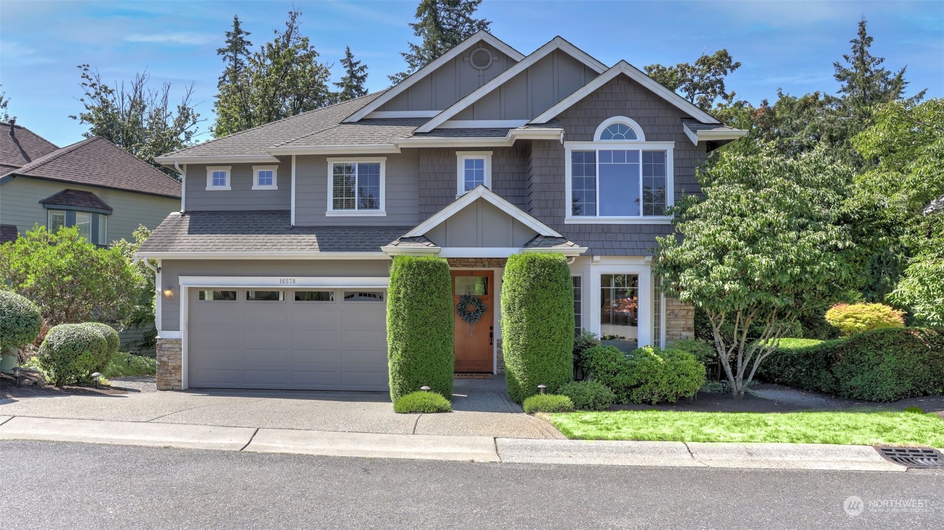 a front view of a house with a garden and trees