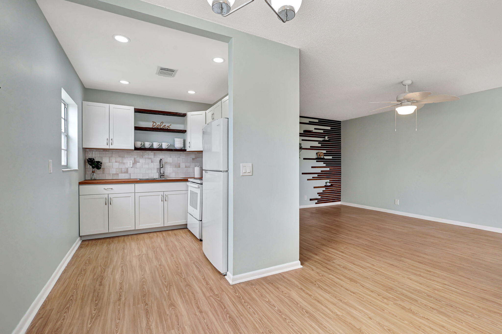 a kitchen with wooden floors white cabinets appliances and a sink