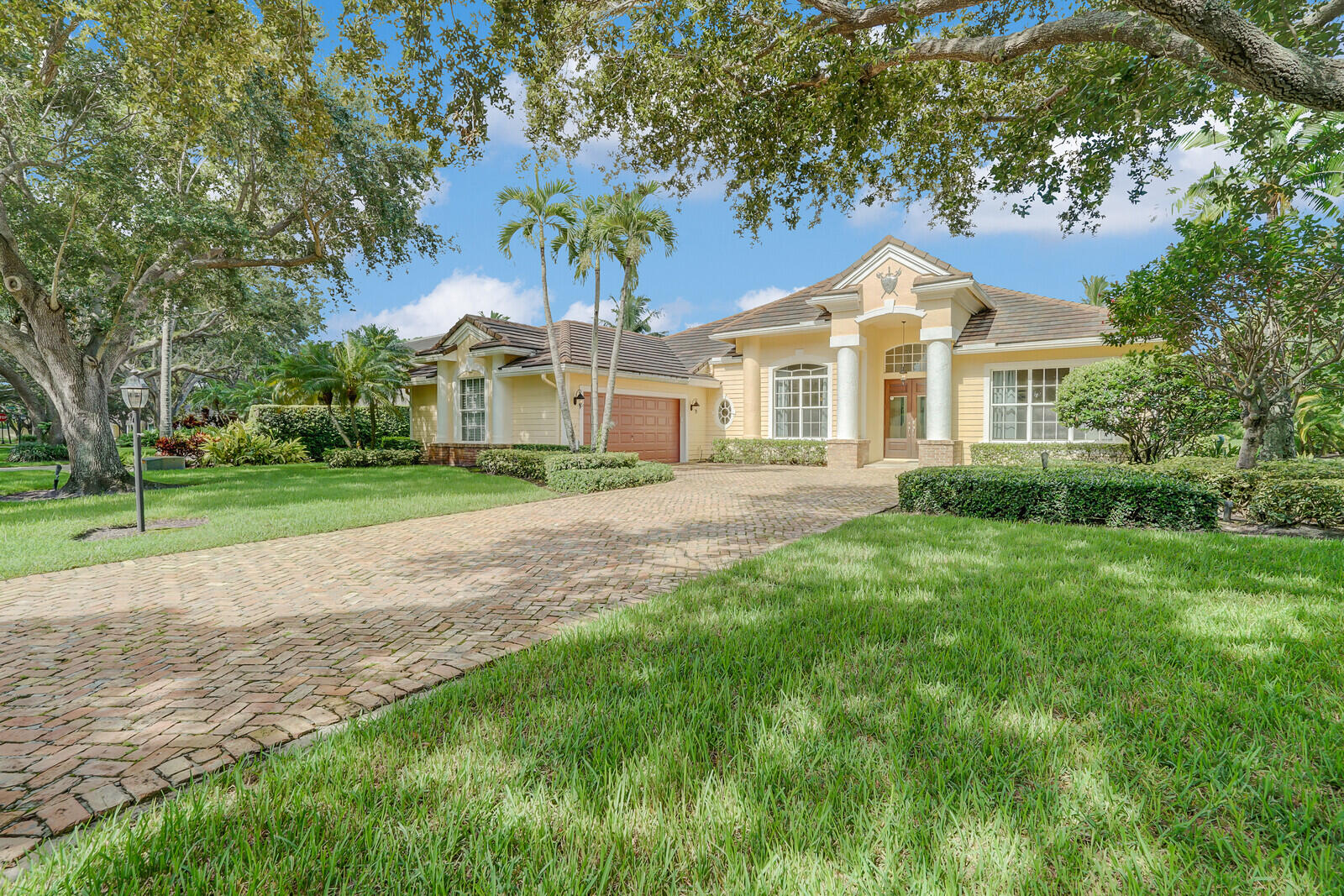 a front view of a house with a garden and trees