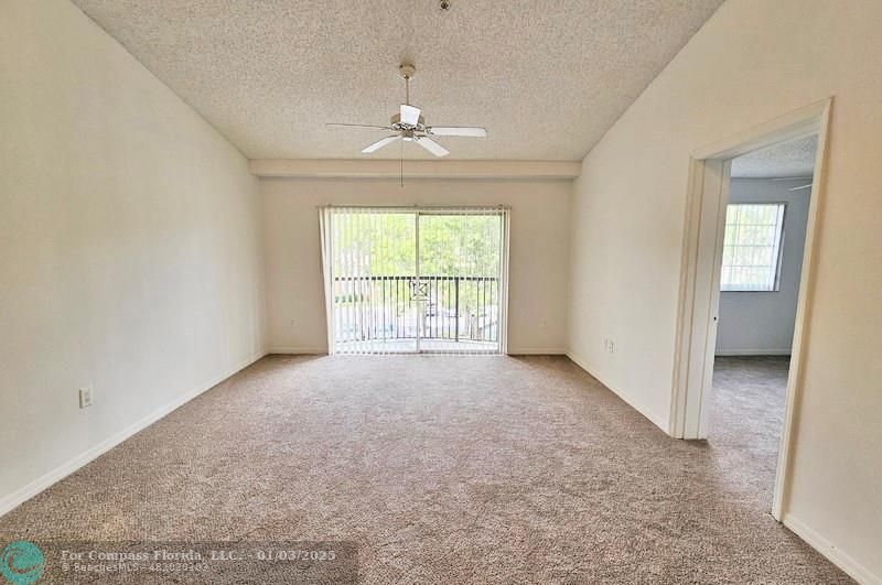 an empty room with chandelier fan and windows