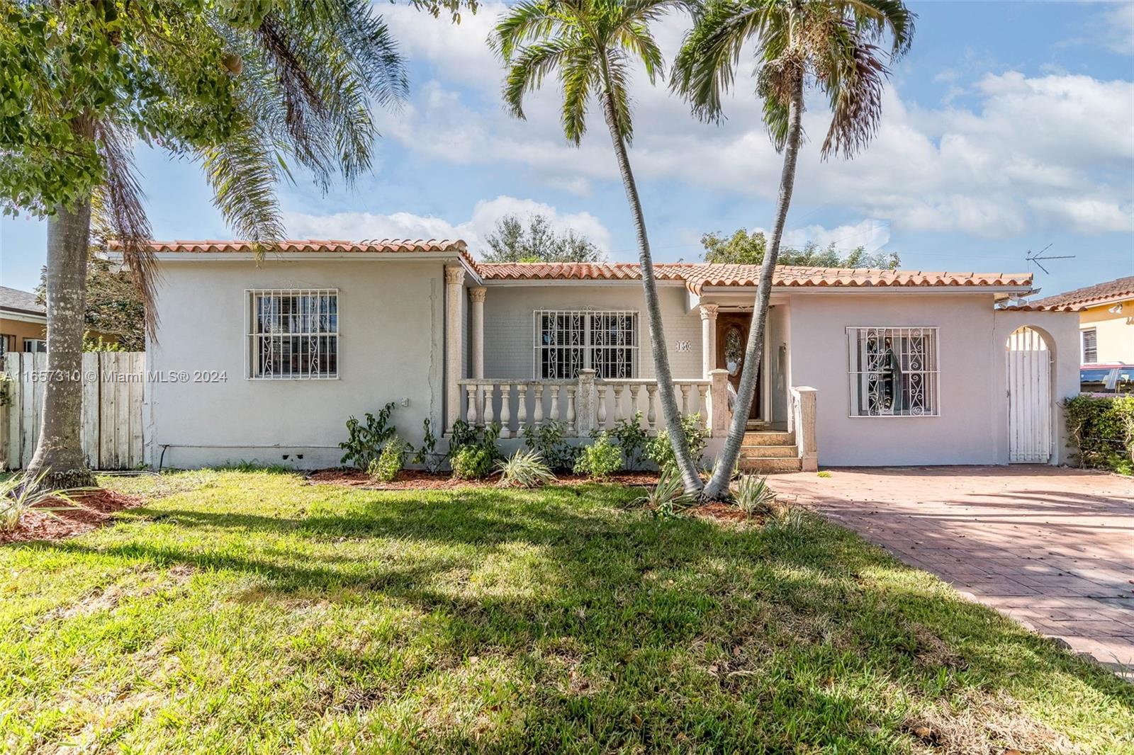 front view of house with a yard and palm trees