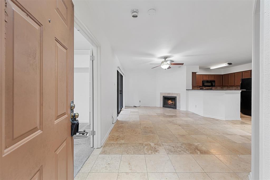 a view of a livingroom with a fireplace a kitchen space and a window