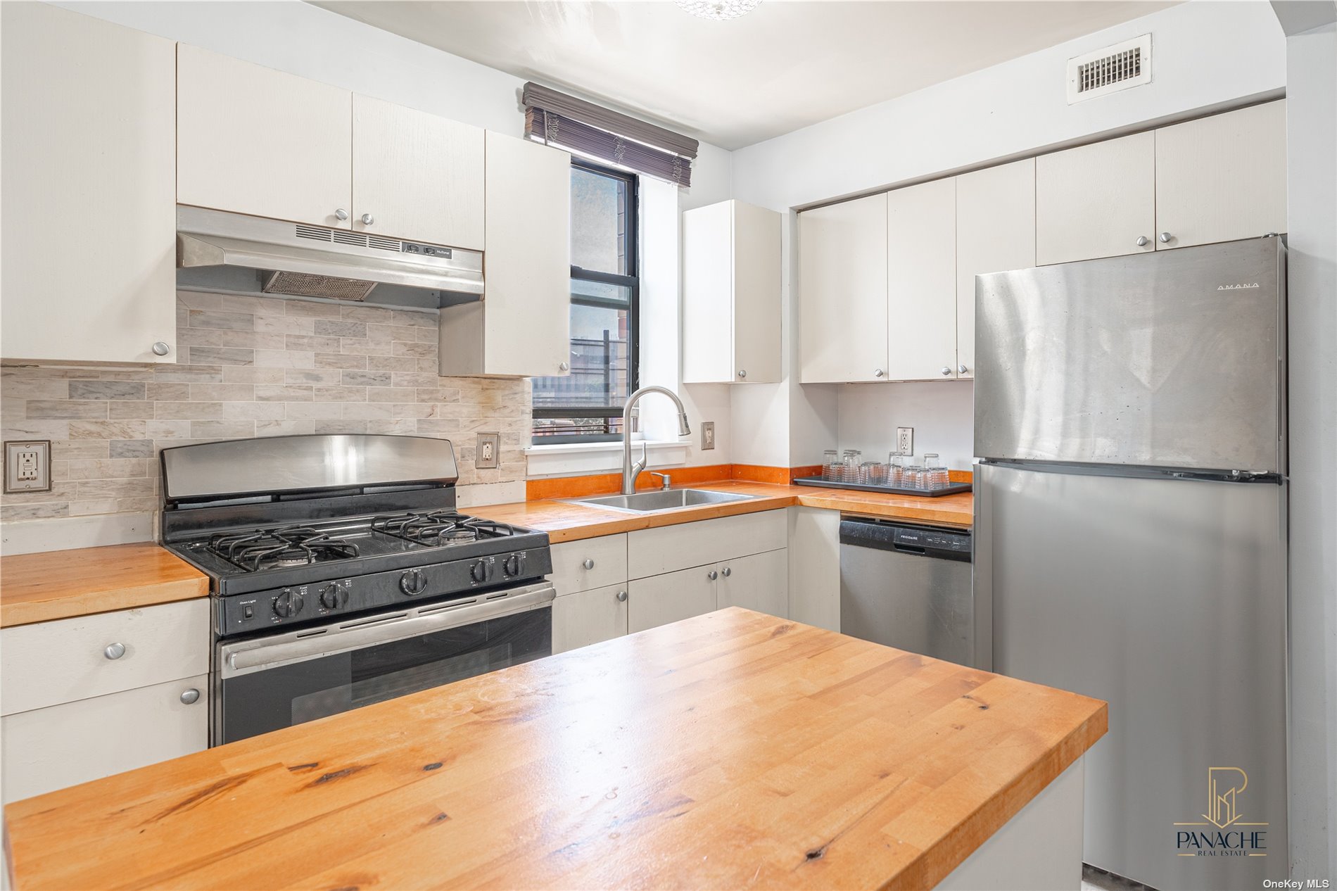 a kitchen with granite countertop a refrigerator stove top oven and sink