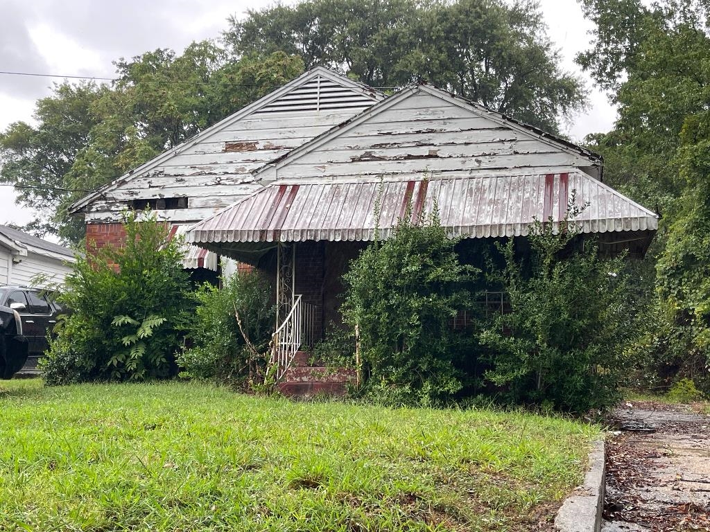 a view of a house with a yard plants and large tree