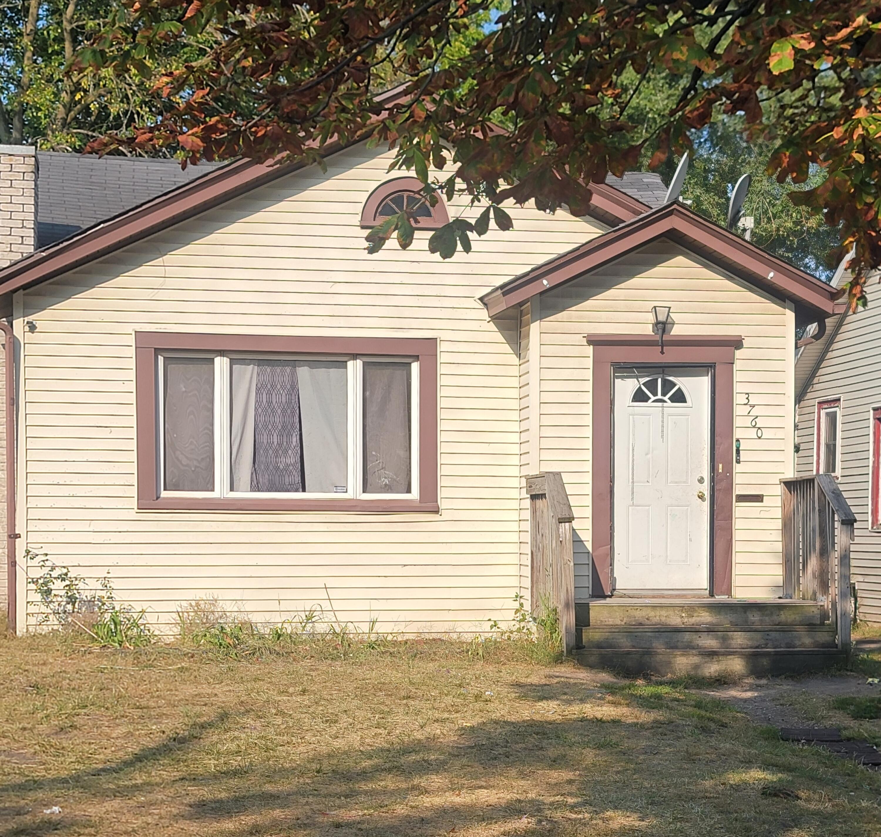 a view of a house with a small yard and a large tree