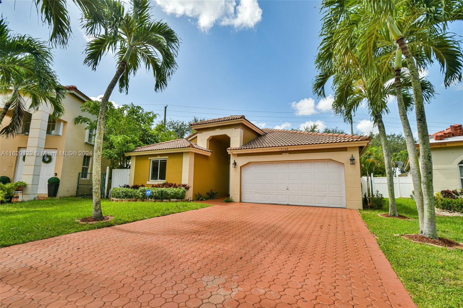 a view of a house with a yard and palm trees