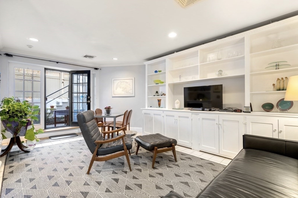 a living room with furniture a flat screen tv and a refrigerator