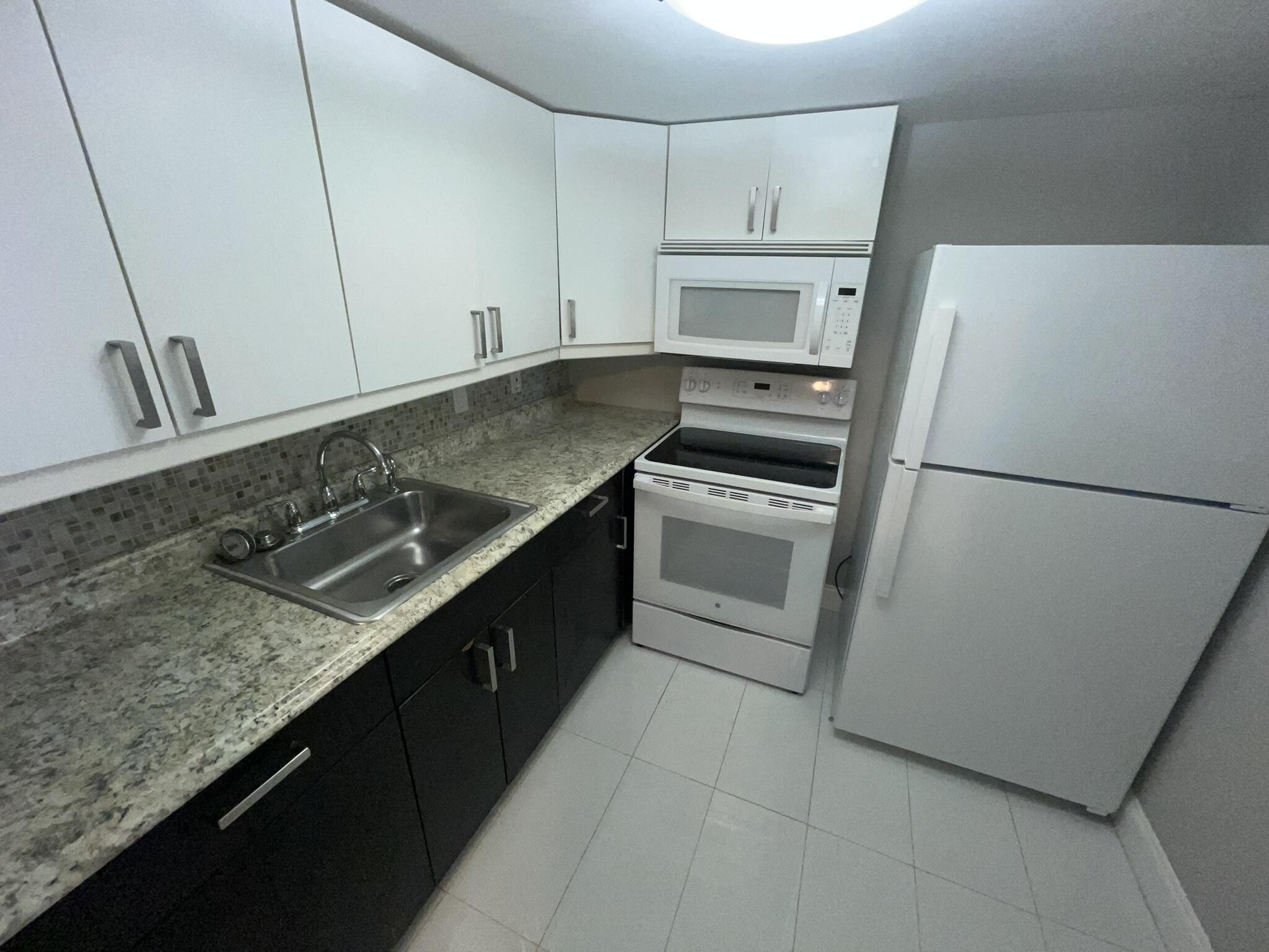 a kitchen with granite countertop a refrigerator sink stove and cabinets