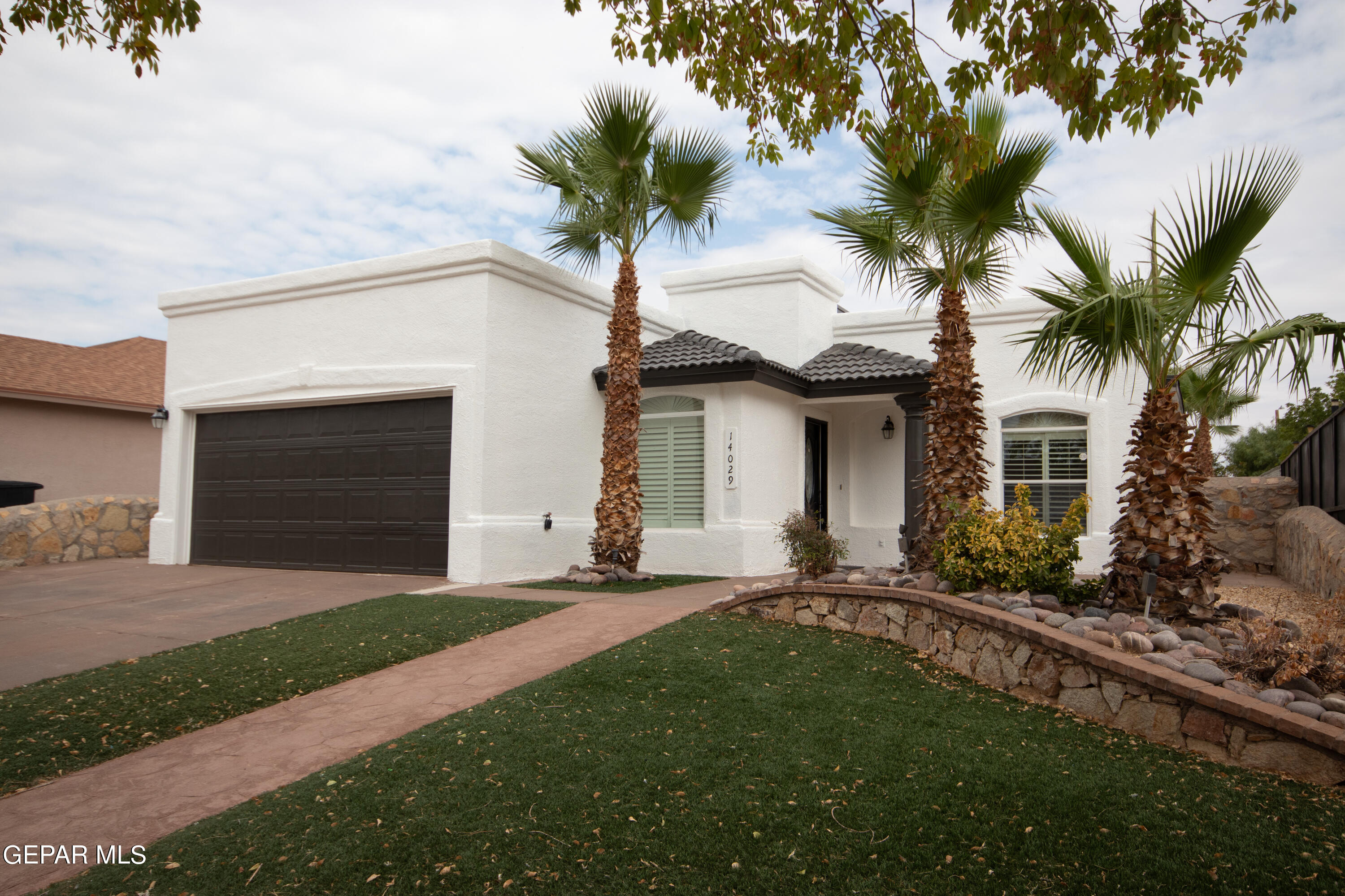 a front view of a house with a garden and trees