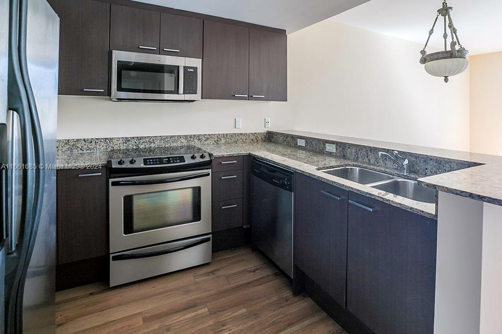 a kitchen with granite countertop cabinets stainless steel appliances and wooden floor