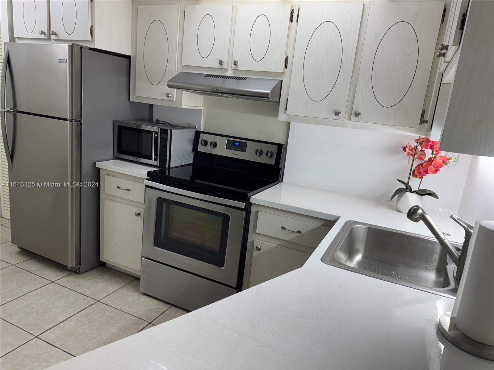 a kitchen with stainless steel appliances granite countertop a sink and a refrigerator