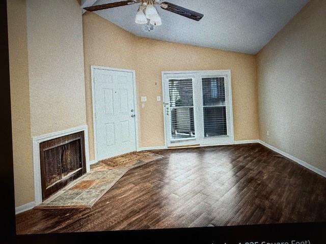 a view of an empty room with a fireplace and wooden floor