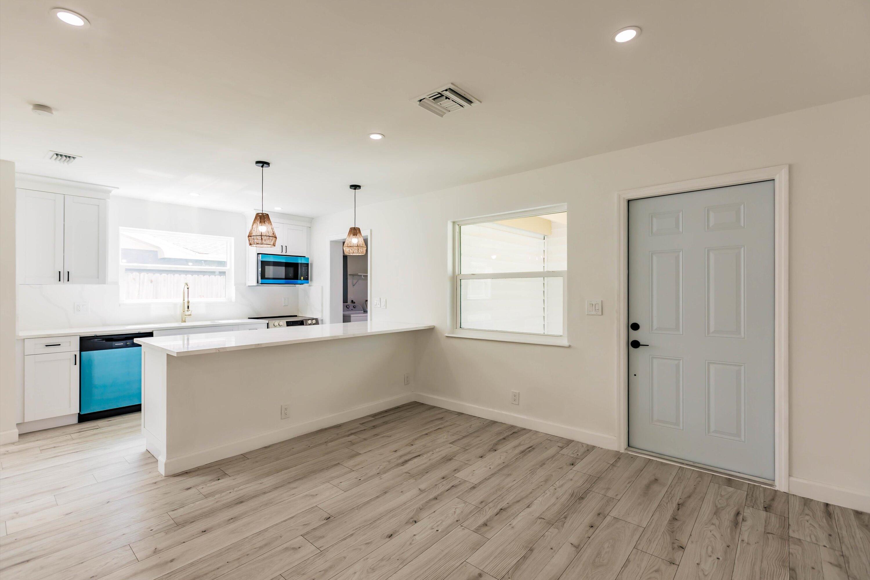 a large white kitchen with wooden floors and white walls