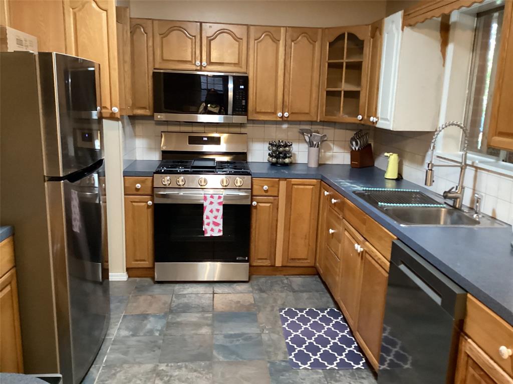 a kitchen with stainless steel appliances granite countertop a sink stove refrigerator and microwave