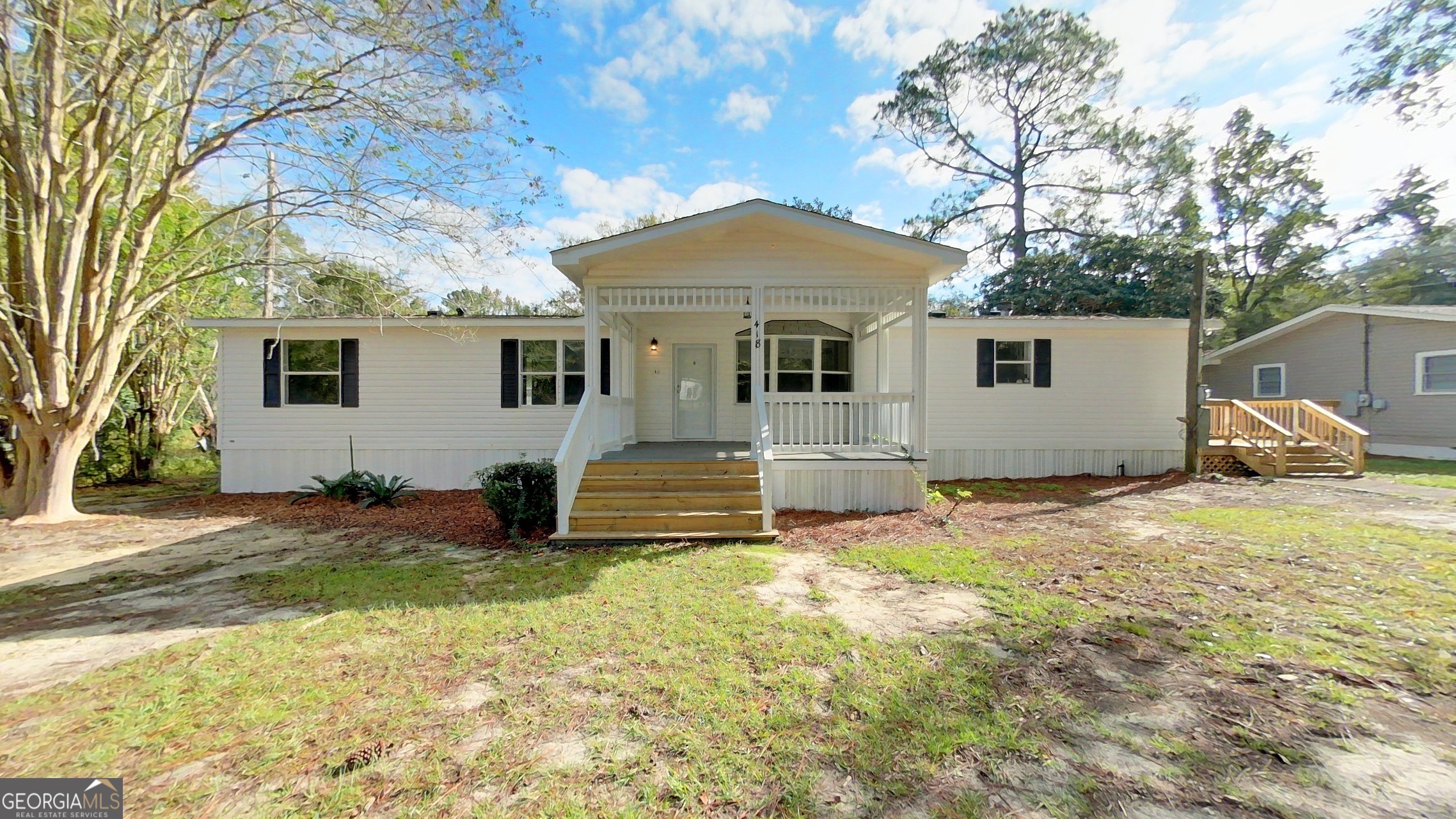 a front view of house with yard and trees in the background