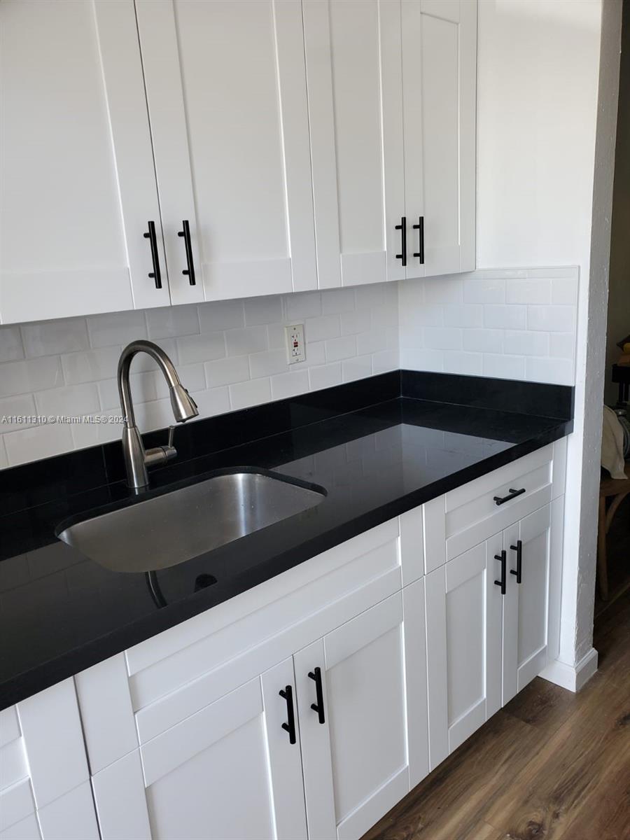 a kitchen with granite countertop white cabinets and sink