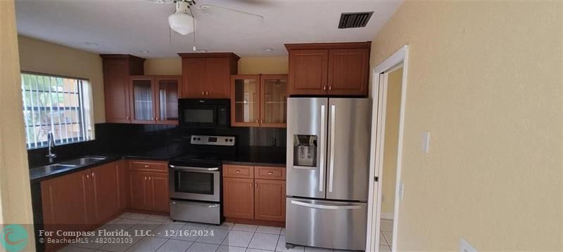 a kitchen with granite countertop a refrigerator a stove and a microwave