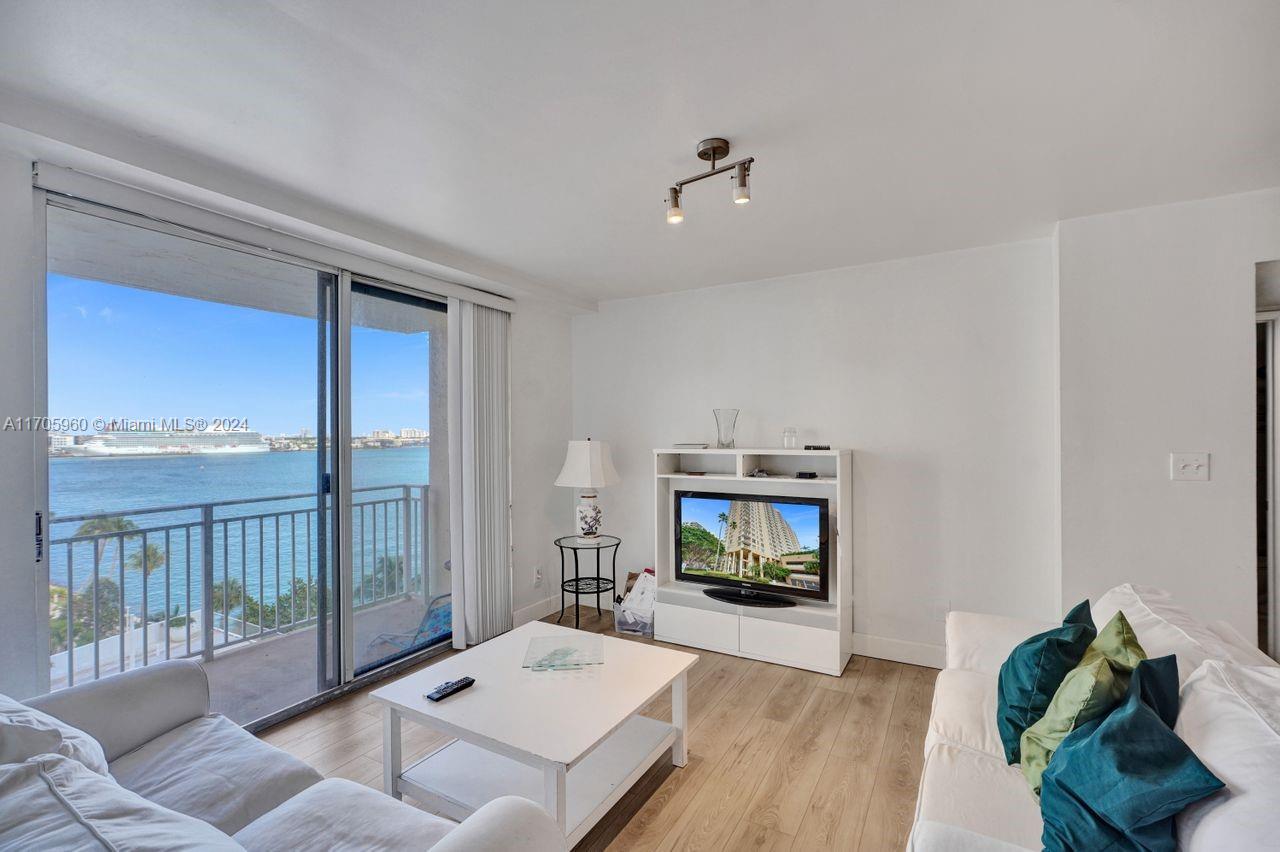 a living room with furniture a flat screen tv and a floor to ceiling window