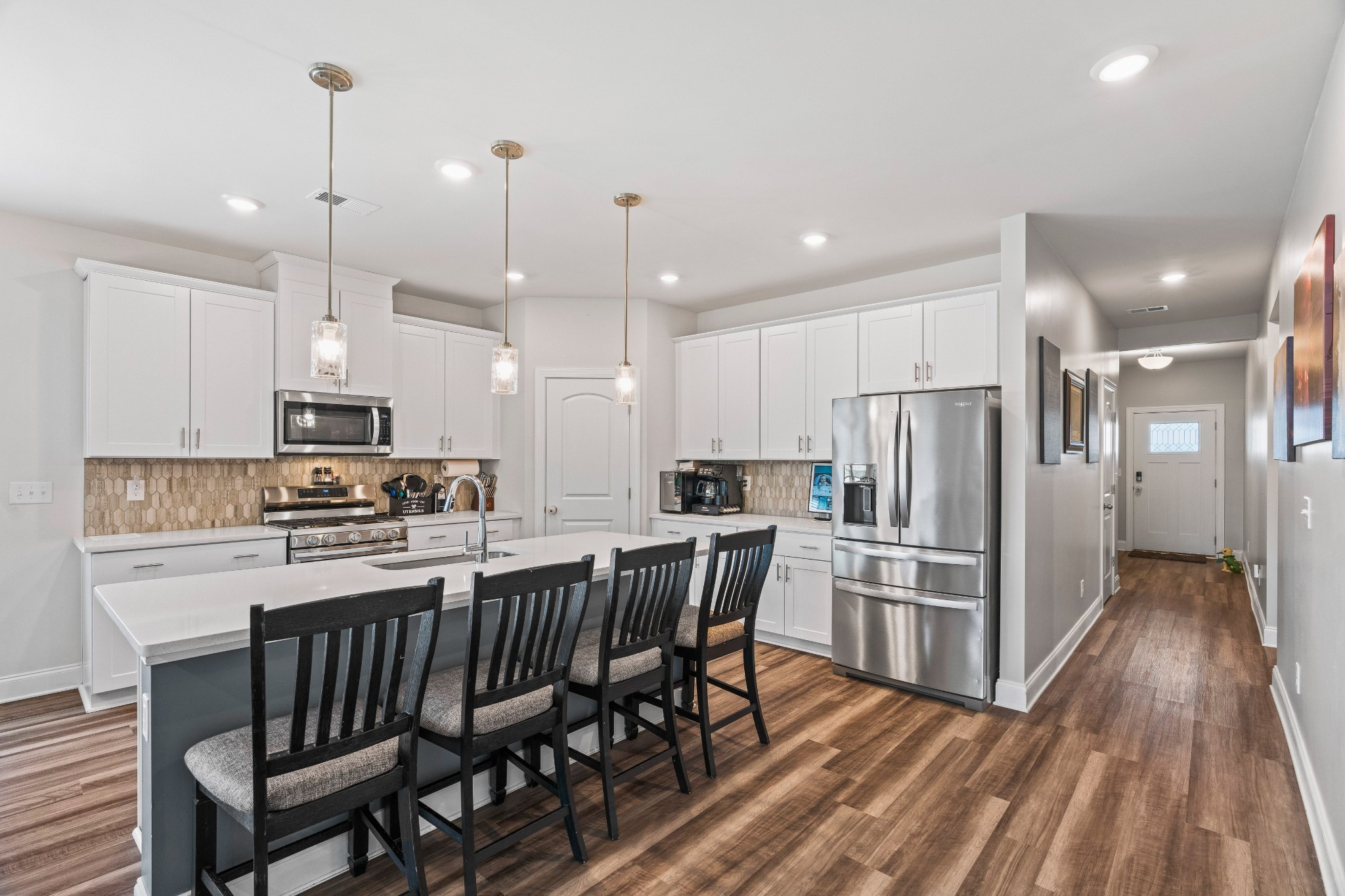 a kitchen with stainless steel appliances granite countertop a refrigerator a stove a sink dishwasher a dining table and chairs with wooden floor