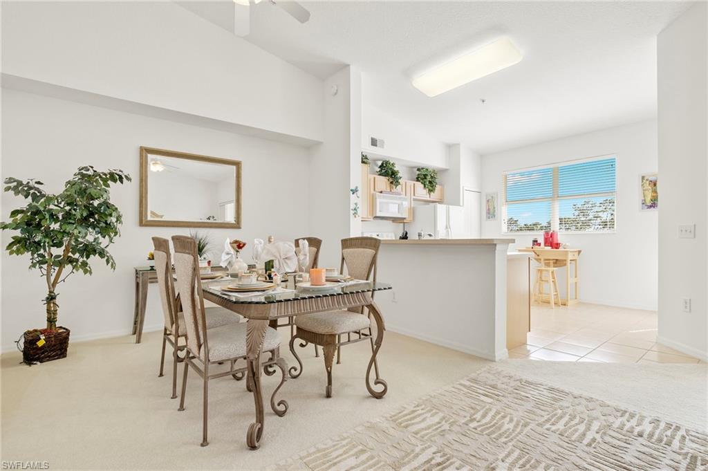 Carpeted dining area featuring high vaulted ceiling and ceiling fan