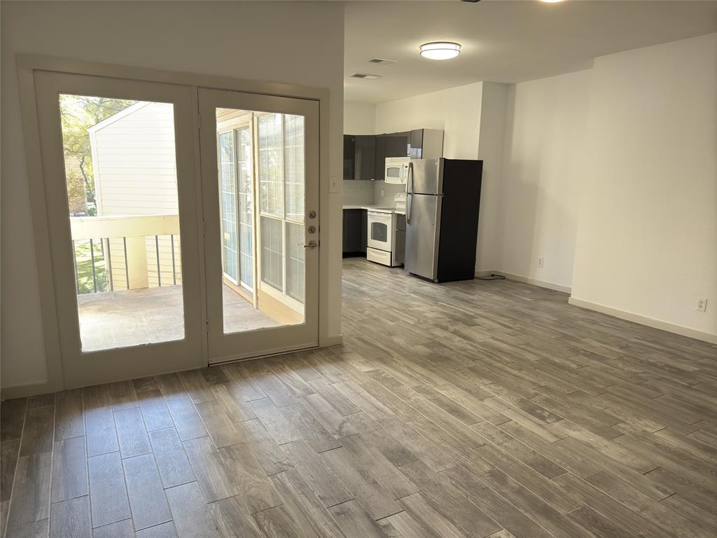 a view of a kitchen with refrigerator and wooden floor