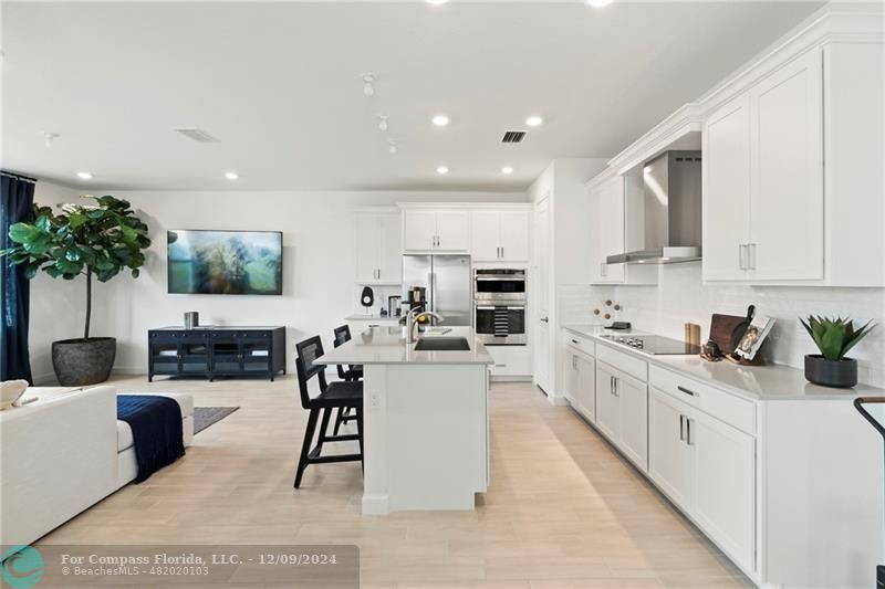 a large white kitchen with lots of counter space a sink and appliances