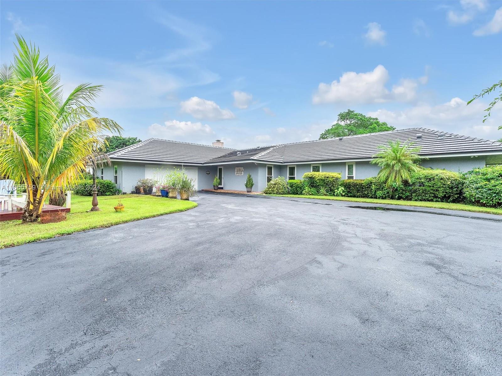 a view of a house with a big yard and palm trees