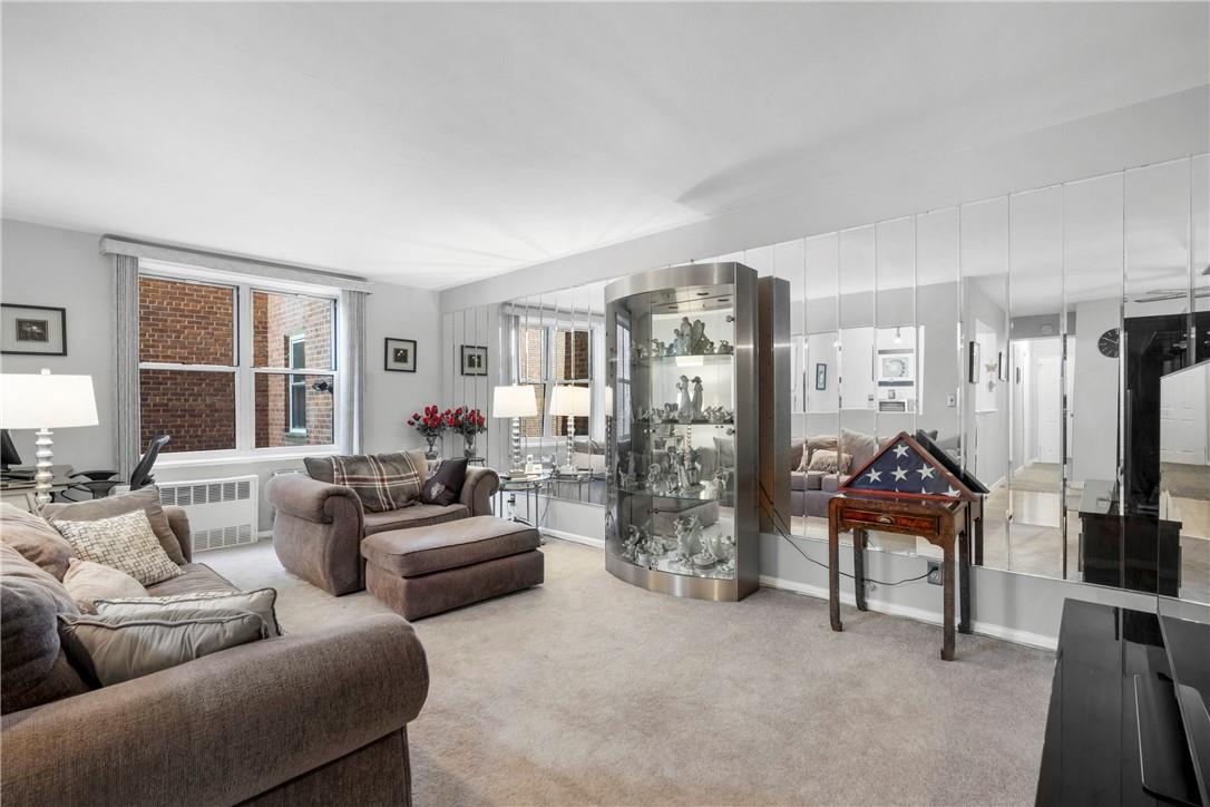 Living room featuring radiator, light colored carpet, and mirrored wall