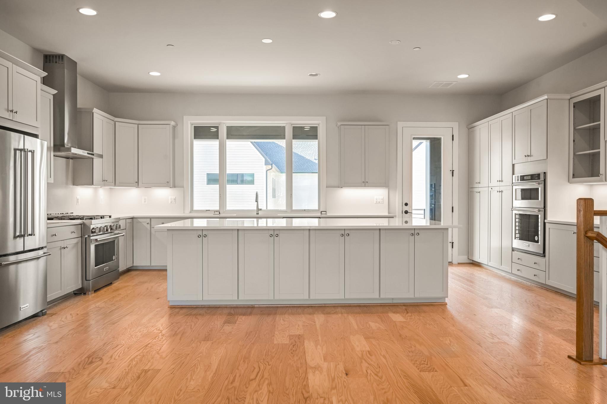 a large kitchen with cabinets wooden floor and stainless steel appliances