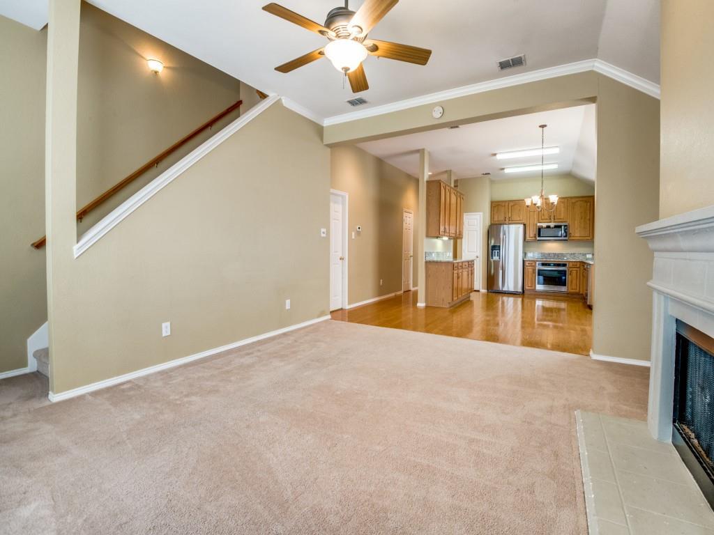 a view of an empty room with kitchen view and a fireplace