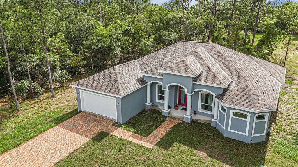 a aerial view of a house with yard and large trees