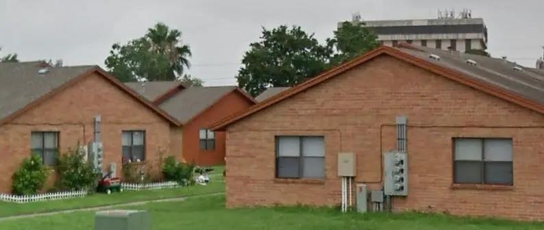 a view of a house with brick walls and a yard with plants