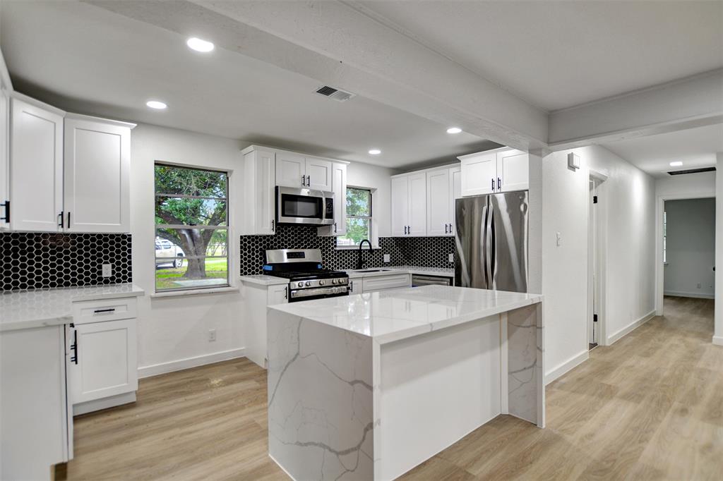 a kitchen with white cabinets and stainless steel appliances