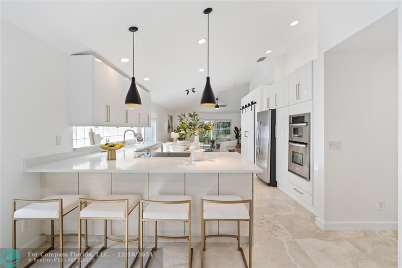 a kitchen with stainless steel appliances kitchen island granite countertop a table chairs and a chandelier