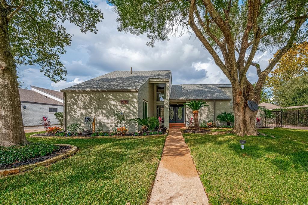 Charming single-story home with well-manicured lawn, mature trees, and a welcoming walkway leading to a cozy entrance. The property features attractive landscaping and a traditional design in the serene neighborhood of Jersey Village.