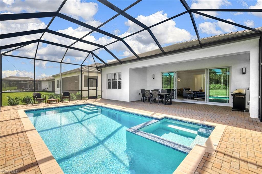 View of swimming pool with an in ground hot tub, a patio area, grilling area, and a lanai