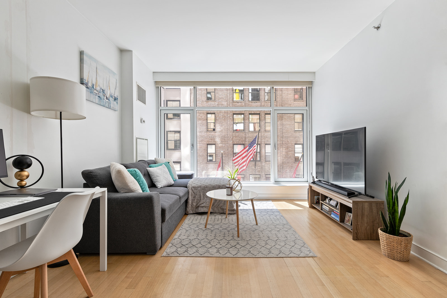 a living room with furniture a flat screen tv and a floor to ceiling window