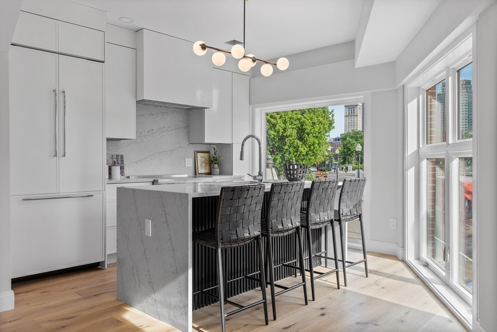 a kitchen with stainless steel appliances granite countertop a table chairs and a refrigerator