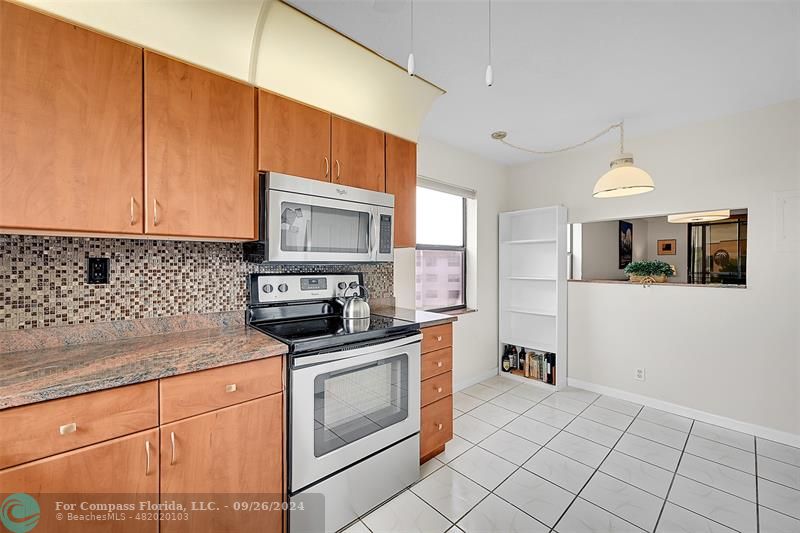 a kitchen with granite countertop white cabinets stainless steel appliances and a sink