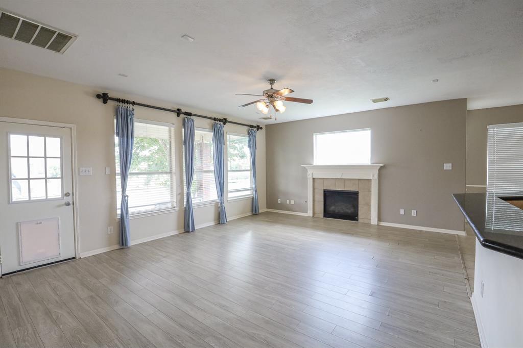 an empty room with windows fireplace and wooden floor