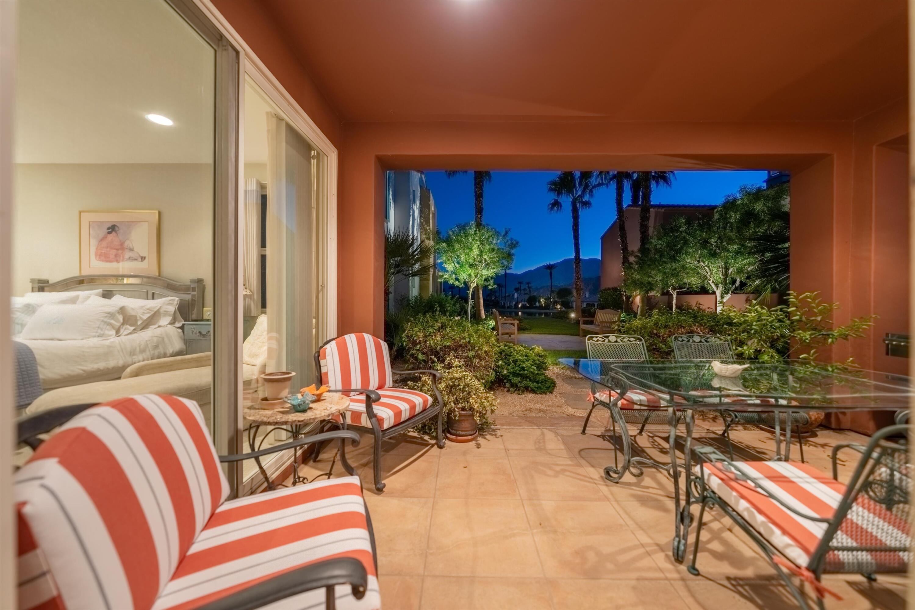 a view of a patio with table and chairs potted plants and floor to ceiling window